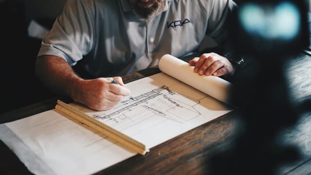 Mains traçant un plan de bâtiment à la règle