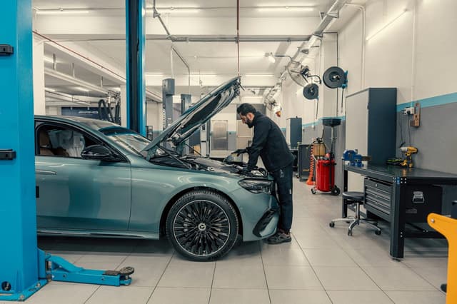 Mécanicien penché sur le moteur d’une voiture dans un atelier