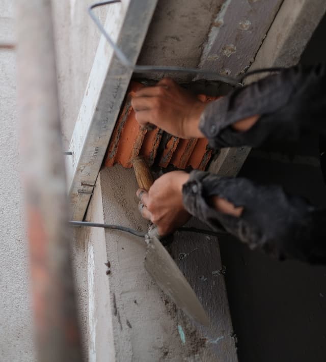 Maçon posant une brique à la truelle